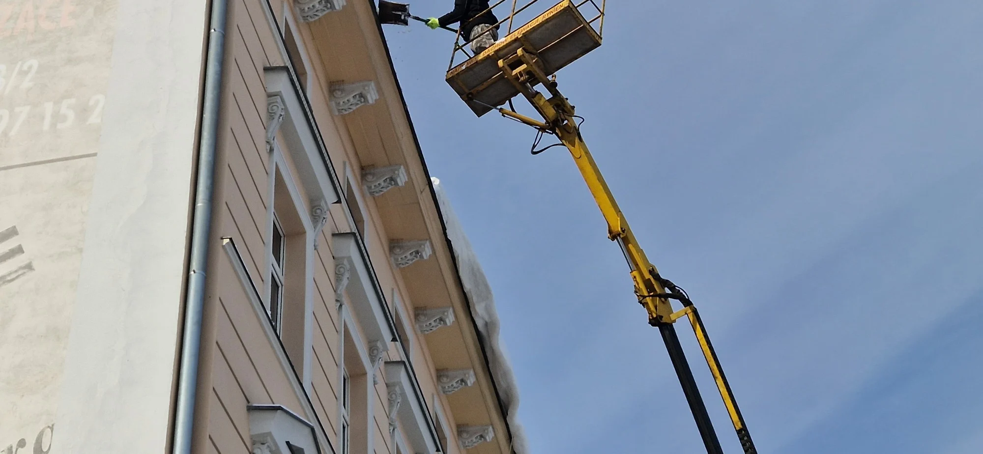Kosz podnośnika PIOTREX przy gzymsie i rynnie kamienicy