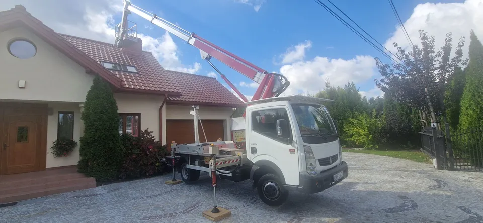 Podnośnik PIOTREX z czerwonym wysięgnikiem przed domem